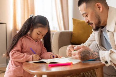 Birlikte öğreniyoruz. Asyalı baba, küçük kızına ders kitabı yazmayı evde resim yapmayı öğretiyor. Babacığın hafta sonu çocuğuna bakıcılık yapıyor.