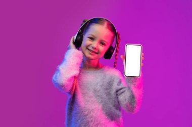 Hoş, güler yüzlü, okul çağında, şık giyinen, kablosuz kulaklık takan, beyaz ekranlı telefon gösteren, neon ışıkta renkli arka plan, güzel müzik uygulaması olan bir kız çocuğu.