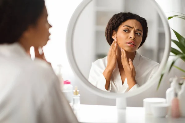自宅でミラーの前に座っている間にチンににきびを見て問題の皮膚を持つ動揺黒人女性 毎日の美容ルーチンを作りながらにきびに気づく心配アフリカ系アメリカ人女性 選択的フォーカス — ストック写真