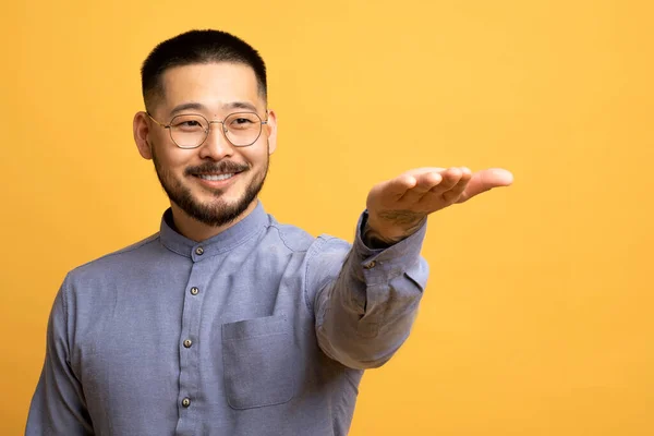 Sorrindo Jovem Asiático Masculino Estendendo Mão Segurando Algo Invisível Palma — Fotografia de Stock
