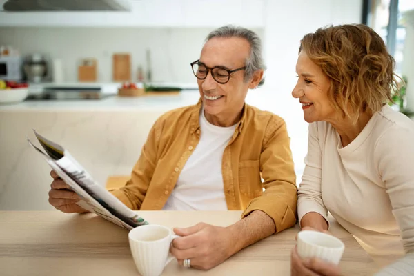 幸せな高齢者の配偶者が一緒に新聞を読んで 家で朝を過ごし お茶やコーヒーを飲んで シニア夫婦は一緒に瞬間を楽しむ — ストック写真