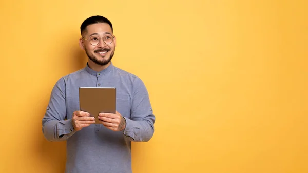 Unga Leende Asiatiska Mannen Håller Digital Tablet Och Ser Bort — Stockfoto