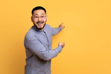 Neşeli Asyalı adam sarı arka planda fotokopi çekmeyi hedefliyor, dövmeleri olan yakışıklı adam reklam için bedava yer gösteriyor ya da tasarım sunuyor, tanıtım yapıyor.