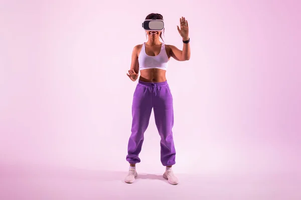 ピンクのネオンの背景にVrヘッドセットを着用し 3D技術と仮想現実ゲームを探索し 幸せなフィットアフリカ系アメリカ人女性 フル長さ フリースペース — ストック写真