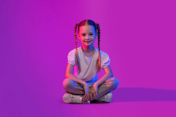 若者の可能性と創造性 未来の天才 かわいい陽気な笑顔かなり小さな学校の女の子が床に座って 明るい色の背景に冷たい コピースペース — ストック写真