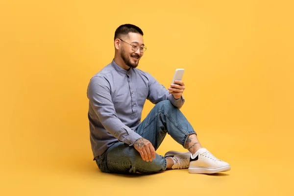 Lächelnder Asiatischer Mann Mit Smartphone Mobile Anwendung Sitzen Über Gelbem — Stockfoto
