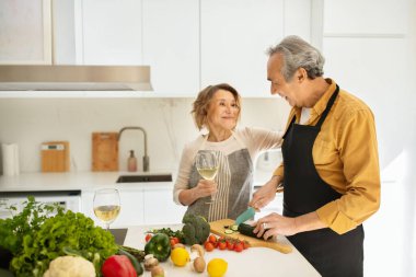 Evlilik yıldönümünü kutlayan mutlu eşleri seven erkekler yemek hazırlarken kadınlar şarap içerken, mutfak içini, fotokopi çekerken.