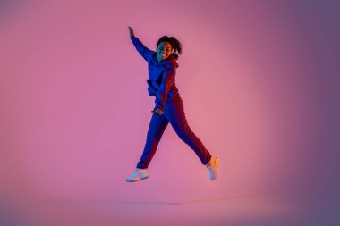 Pembe neon arka planda zıplayan heyecanlı zenci kadın portresi, boş alan. Gençlik, duygular, hareket, hareket, reklam