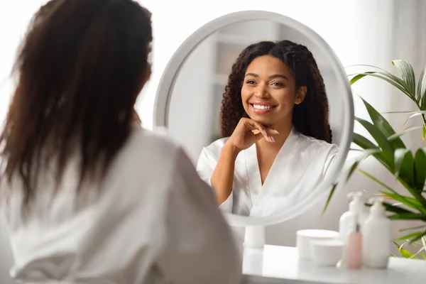 美の概念 自宅で鏡を見ている魅力的な黒人女性の肖像 美しいアフリカ系アメリカ人女性は ドレッシングテーブルに座っていると反省に笑みを浮かべて 選択的フォーカス — ストック写真