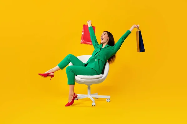 Sarı Arka Planda Başarılı Bir Alışveriş Sonrası Kese Kağıdıyla Sandalyede — Stok fotoğraf