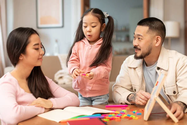Early Education With Parents. Asian Father And Mother Teaching Preschool Little Daughter To Read, Playing With Magnetic Board And Letters At Home. Learning Games Advertisement