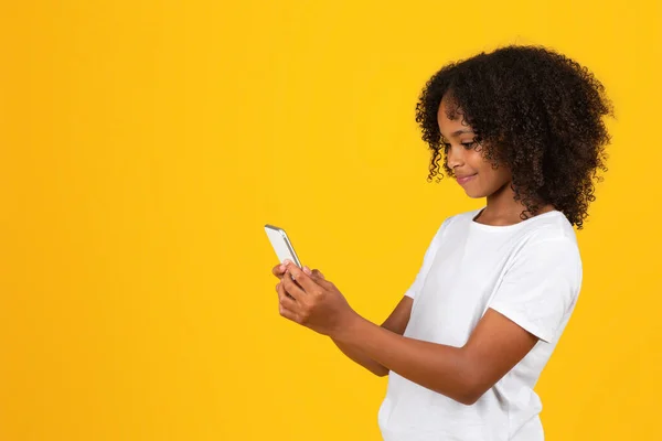 티셔츠를 스튜디오 배경에 고립된 전화로 타이핑하는 곱슬곱슬 아프리카 미국인 학습을 — 스톡 사진