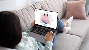 Dizüstü bilgisayarı olan ve evden internetten alışveriş yapan Millennial Hintli kadın, ekrandaki kıyafetlere bakın. Genç bayan müşteri boş zamanların ve alışverişin tadını çıkarıyor.