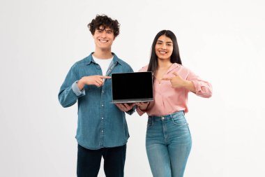E-Öğrenme Teklifi. Eğitim sitesi reklamı için dizüstü bilgisayarı olan mutlu öğrenci çifti beyaz stüdyo arkaplanı yerine bilgisayarı işaret ediyor. Model