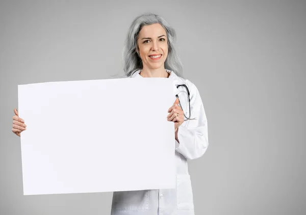 Ιατρική Διαφήμιση Ώριμη Γυναίκα Γιατρός Δείχνει Μεγάλο Πανό Χαρτί Στέκεται — Φωτογραφία Αρχείου