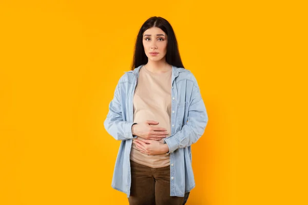 Kafkasyalı Hamile Kadının Portresi Göbeğine Dokunuyor Kameraya Bakıyor Sarı Stüdyo — Stok fotoğraf