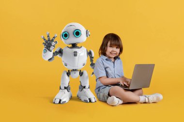 Çocuklar için robotik, programlama ve mühendislik. Dizüstü bilgisayarı olan, kameraya gülümseyen, yanında poz veren, turuncu stüdyo geçmişi olan sevimli bir çocuk.