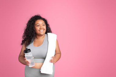 Spor kıyafetli, elinde havlu şişesi olan, spor kıyafetli mutlu bir siyah kadın. Pembe arka plandaki egzersizden sonra dinleniyor, kopyalama alanı. Spor, spor ve antrenman için su dengesi