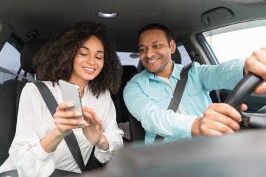 Navigasyon konsepti. Neşeli Arap çift, araba sürerken yön ve güzergah planlaması için telefonda GPS uygulaması kullanıyor. Eşler akıllı telefondan seyrüsefer için yeni araç kullanıyorlar