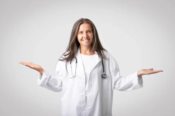 Весела Жінка Лікар Яка Тримає Щось Невидиме Обох Руках Посміхається — стокове фото