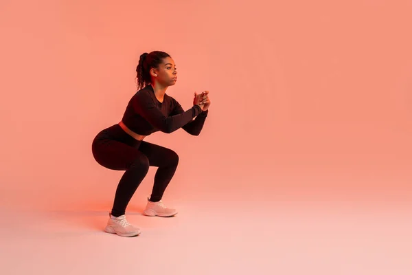 Genç Siyahi Kadın Derin Çömelmeler Yapıyor Stüdyoda Kırmızı Neon Arka — Stok fotoğraf