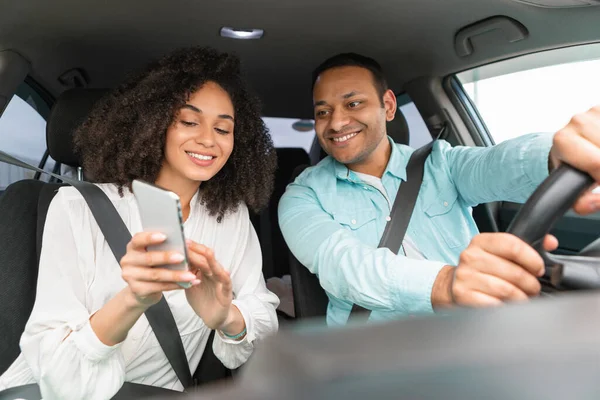 stock image Navigation Concept. Cheerful arabic couple using GPS app on phone for direction and route planning during a drive. Spouses driving new vehicle together navigating via smartphone