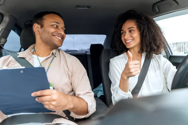 運転免許証を取得する 講師が合格試験に合格するまで笑顔で親指を立てる幸せなアラビア人ドライバー女性は 車の中で座ります レディーラーナープロコーチとのレッスン承認 — ストック写真