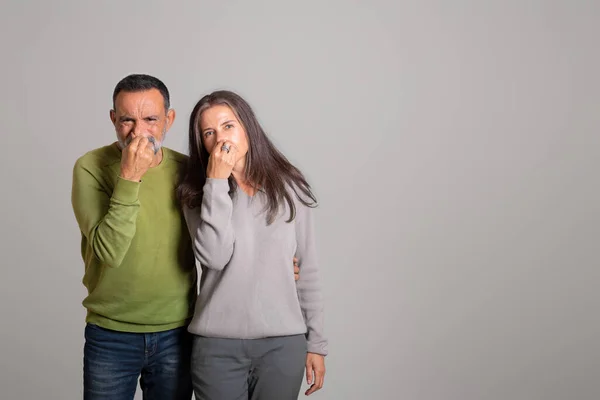 悲しい怒っているヨーロッパの老夫婦は 手で鼻をカバー灰色のスタジオの背景に臭いと悪い匂いに苦しんでいます 人々の感情 ストレスや嫌悪感 衛生上の問題 オファー — ストック写真