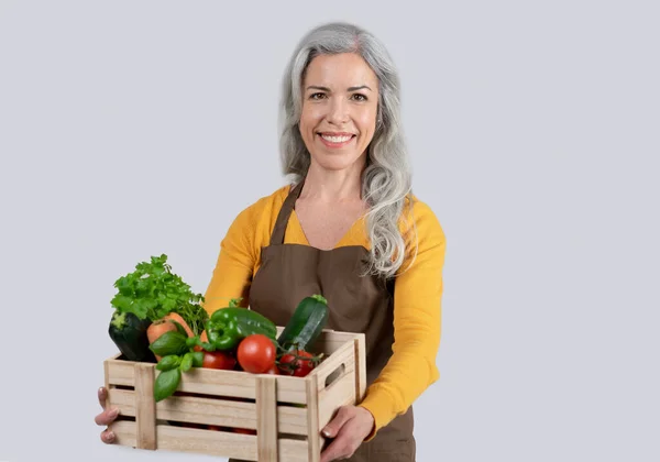 Önlüklü Yaşlı Avrupalı Gri Saçlı Kadının Organik Sebzeli Ahşap Kutuyu — Stok fotoğraf