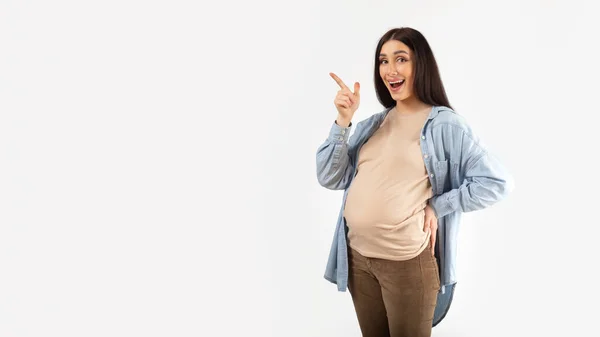 妊娠中の広告 白い背景にコピースペースで脇を指して興奮妊婦 パノラマ あなたのデザインや広告のための場所を示す感情的な美しい期待の女性 — ストック写真