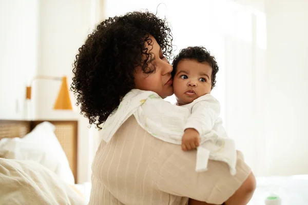 Havluyla Küçük Bebeğini Öpen Mutlu Siyah Kıvırcık Saçlı Milenyum Annesi — Stok fotoğraf
