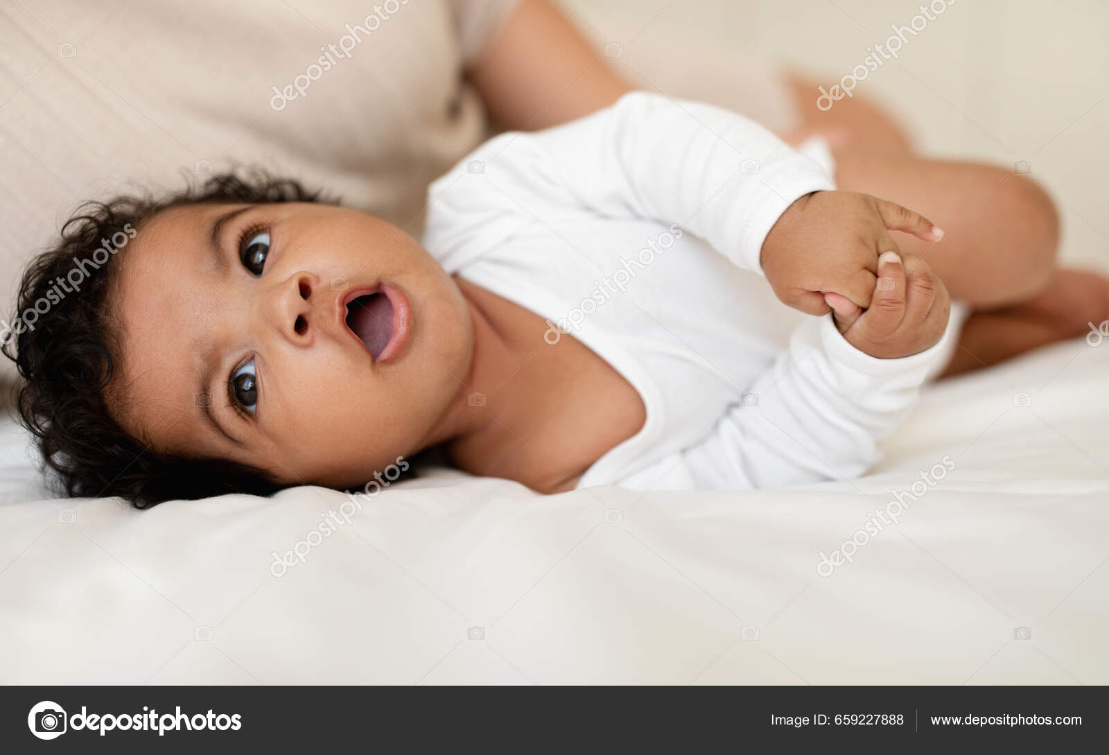 Free Photo  Young beautiful happy mother in sleepwear and her newborn baby  sitting on bed in morning smiling playing together.