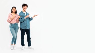 Şuraya bak. Neşeli genç çift fotokopi uzayı gösteriyorlar. Parmak gösteriyorlar. Stüdyoda Beyaz Arkaplan 'ın üstünde duruyorlar. Esmer Kız Arkadaşı ve Erkek Arkadaşı Gençlik İçin Harika Bir Teklif Veriyor. Panorama