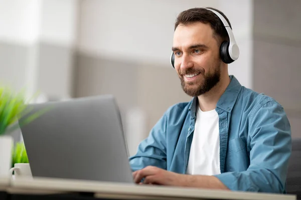Uśmiechnięty Męski Pracownik Noszący Słuchawki Bezprzewodowe Pracujący Komputerze Nowoczesnym Biurze — Zdjęcie stockowe
