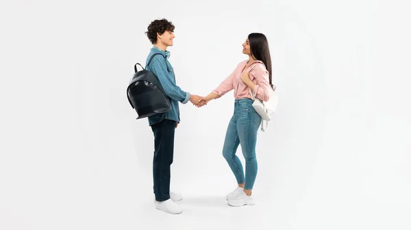 新しい友人と会う 幸せな学生のカップルは 大学での初日に握手挨拶を交わし 白いスタジオの背景に立っています こんにちは あなたのコンセプトを満たすためにニース フルレングスショット パノラマ — ストック写真