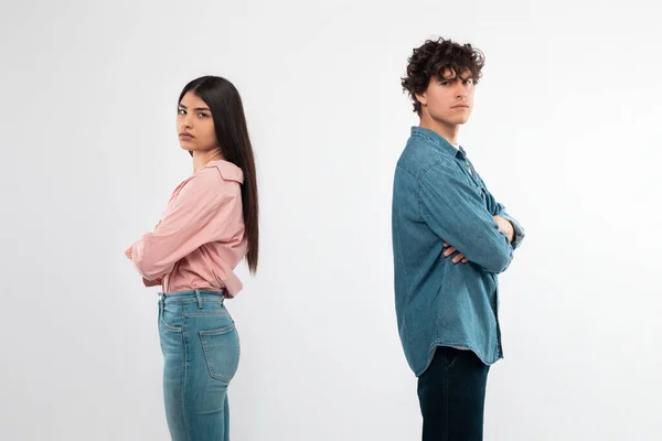 Breakup. Offended Couple After Conflict Standing Back To Back Looking At Camera Over White Background In Studio. Shot Of Unhappy Young Girlfriend And Boyfriend Having Disagreement. Bad Relationship