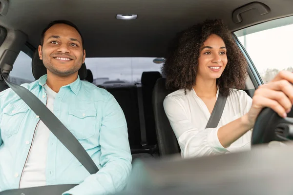 stock image Driving Lessons Concept. Happy Middle Eastern Driving Instructor Teaching Driver Lady To Drive Car, Sitting With Fastened Seat Belts. Man Guiding Young Learner Through Traffic Basics