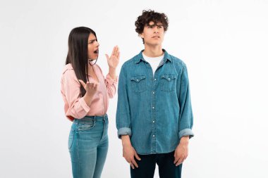 Sorunlu ilişki. Beyaz arka planda duran duygusal kız arkadaş, erkek arkadaşına bağırıyor ve kavga ediyor. Stüdyoda çekilen mutsuz genç çiftin çakışmaları. Anlaşmazlık ve Ayrılık