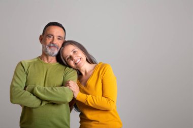 Neşeli Avrupalı yaşlı karı ve koca, gri stüdyo arka planında, boş zamanlarında buluşmanın keyfini çıkarıyorlar. Aile ilişkisi, romantizm ve pozitiflik, yaşam tarzı, reklam ve teklif