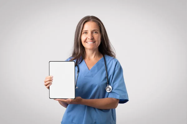 Radosna Europejska Lekarka Pokazująca Cyfrową Tabletkę Białym Czystym Ekranem Polecająca — Zdjęcie stockowe