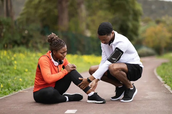 Σοβαρός Νεαρός Μαύρος Αθλητικά Βοηθά Γυναίκα Κάθεται Στο Δρόμο Υποφέρει — Φωτογραφία Αρχείου