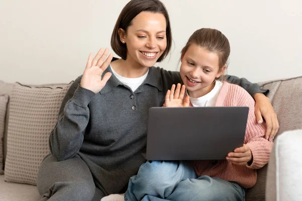 快乐的高加索中年妈妈和小女儿挥挥手 看着电脑 问候语 在客厅里打招呼 视频通话 远程通信 — 图库照片