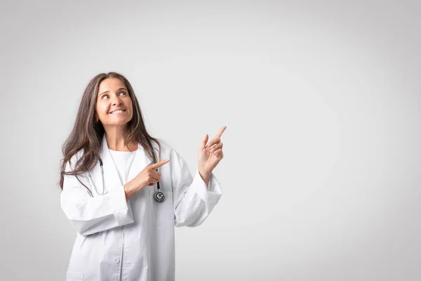 Glimlachende Vriendelijke Blanke Senior Arts Medische Werkkleding Wijzend Naar Kopieerruimte — Stockfoto