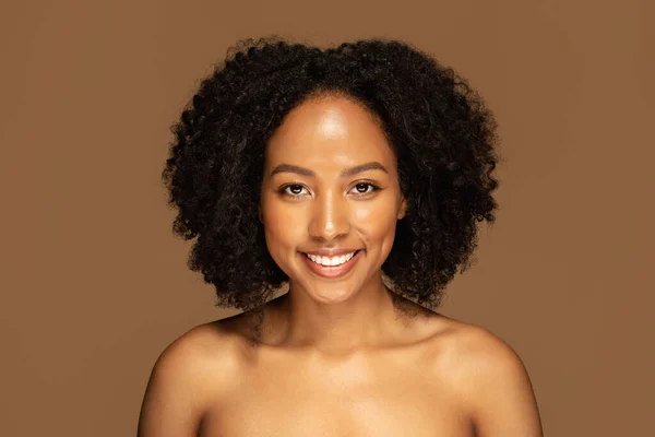 Natural Beauty Concept. Headshot of cheerful smiling attractive young black woman with bushy hair posing naked on colorful studio background, free from artificial enhancements