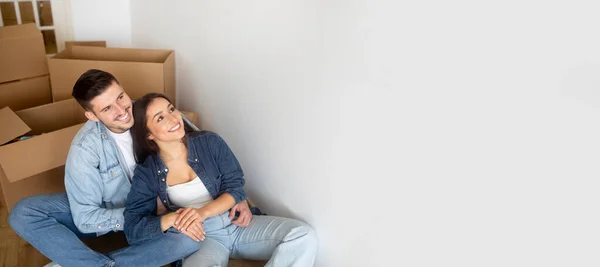 移动广告 快乐的年轻夫妇坐在纸板箱中 远眺复印空间 在搬迁后的新居中微笑欧洲夫妇的室内设计 — 图库照片
