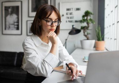 Kadınlar iş başında. Resmi kıyafetli odaklanmış genç bayan yönetici dizüstü bilgisayarın önünde CEO 'su modern ofiste pazarlama raporu üzerinde çalışıyor.