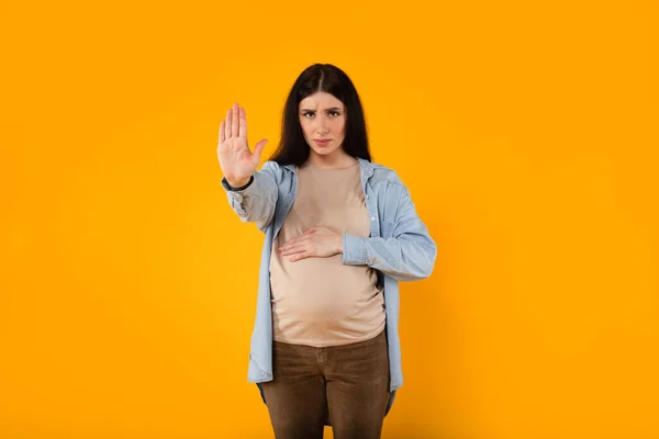 站在你的立场 期待妈妈用停止手势表示不同意 用消极严肃的手势表示警告 站在黄色的背景上 — 图库照片