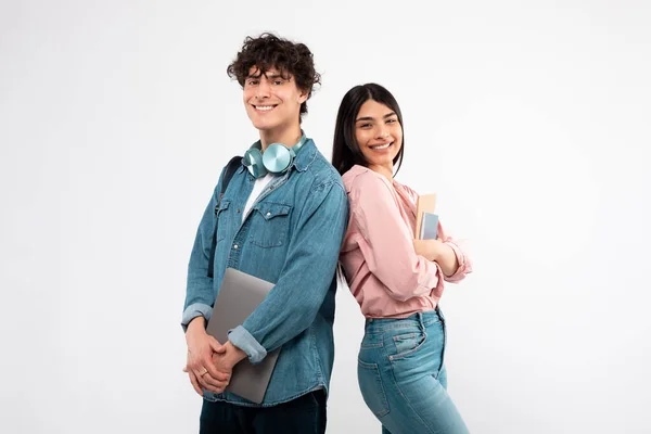 現代の学生 ノートパソコンとワークブックを持つ幸せな若いカップルは ホワイトスタジオの背景に背を向けて立ち カメラに微笑む テクノロジーと教育 優れたEラーニングの提供コンセプト — ストック写真