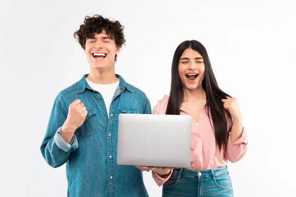 Eラーニングの成功 感情的な若いカップルは ラップトップコンピュータのジェスチャーを保持していますはい喜びで ホワイトスタジオの背景に立つデジタル勝利を祝います 素晴らしいオンラインニュースコンセプト — ストック写真