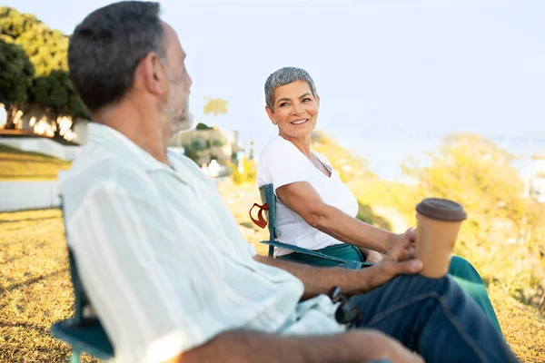 周末的氛围 快乐的年长配偶坐在公园外面的椅子上 喝着纸杯里的咖啡 一起享受夏日 快乐与关系 选择性焦点 — 图库照片